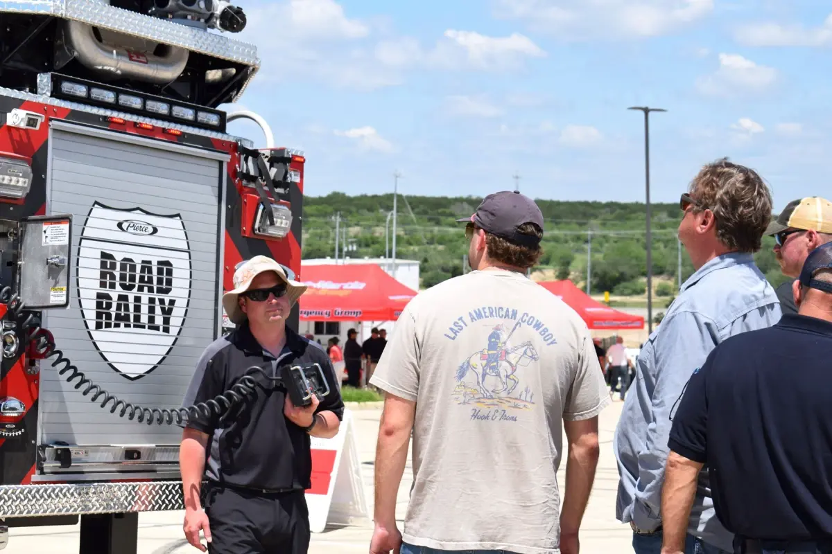 Firefighters and attendees inspect a fire truck at a Pierce Manufacturing Road Rally event.