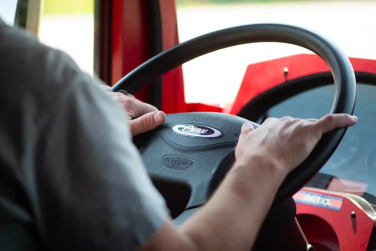 A driver's hands on the steering wheel of a red Pierce fire truck during a Road Rally test drive.