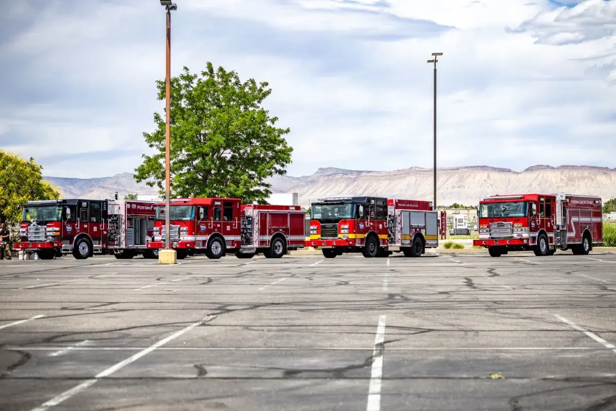 Four Pierce fire trucks parked in a row with mountains in the background during the Pierce Road Rally.