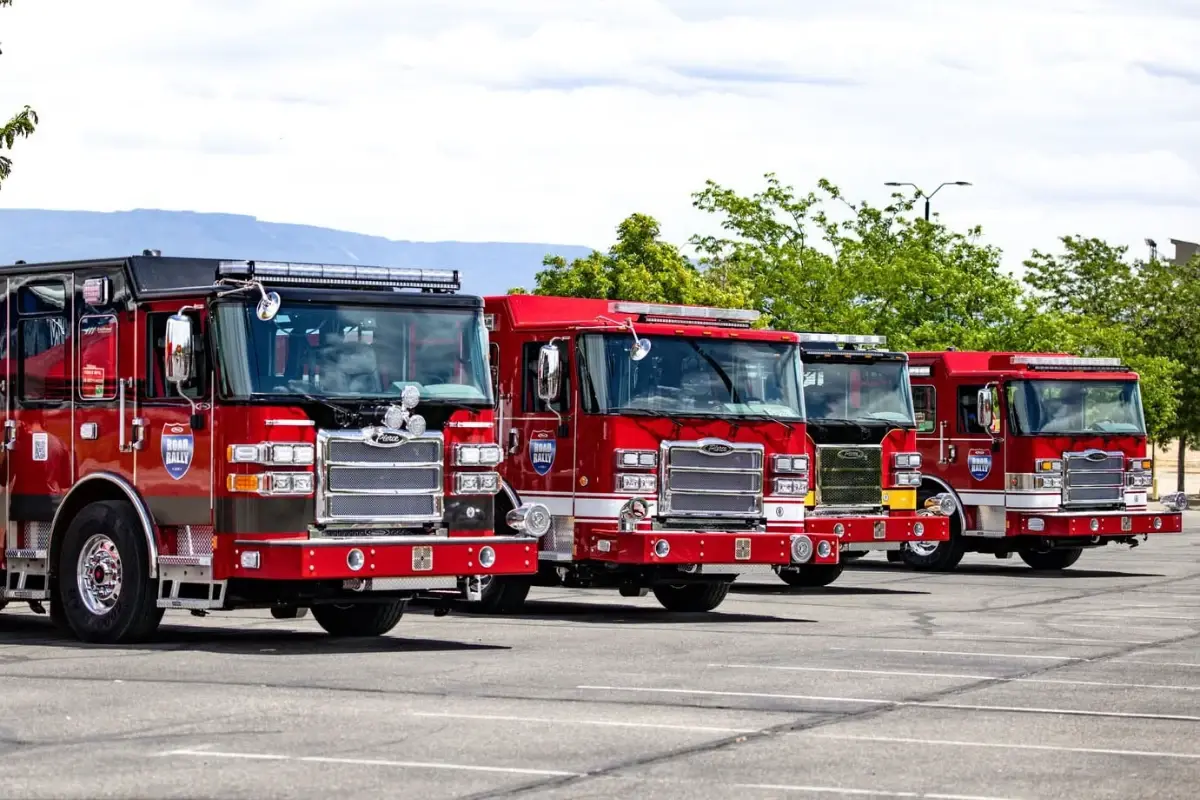 Four red Pierce fire trucks parked in a row during a Road Rally event.