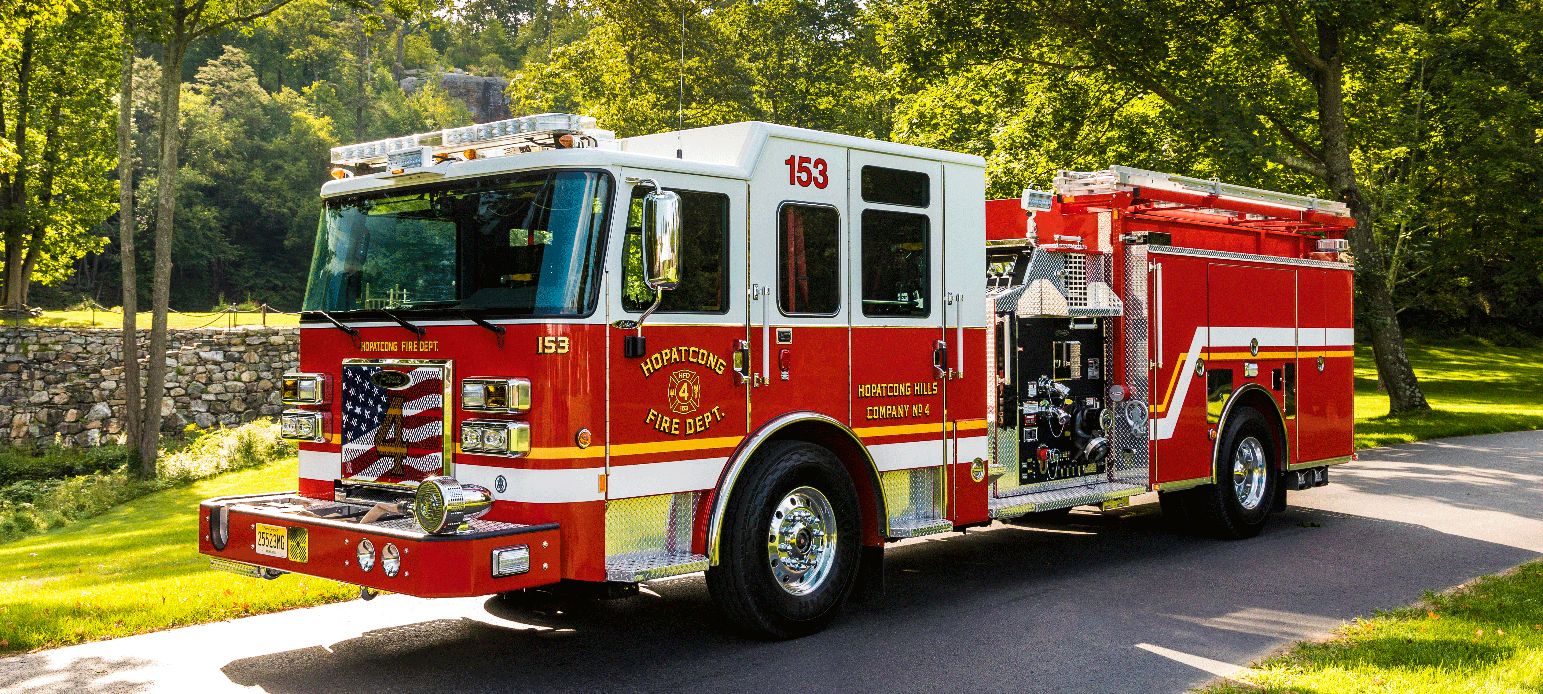 Pierce Saber custom fire truck parked outside on a sunny day surrounded by trees. 