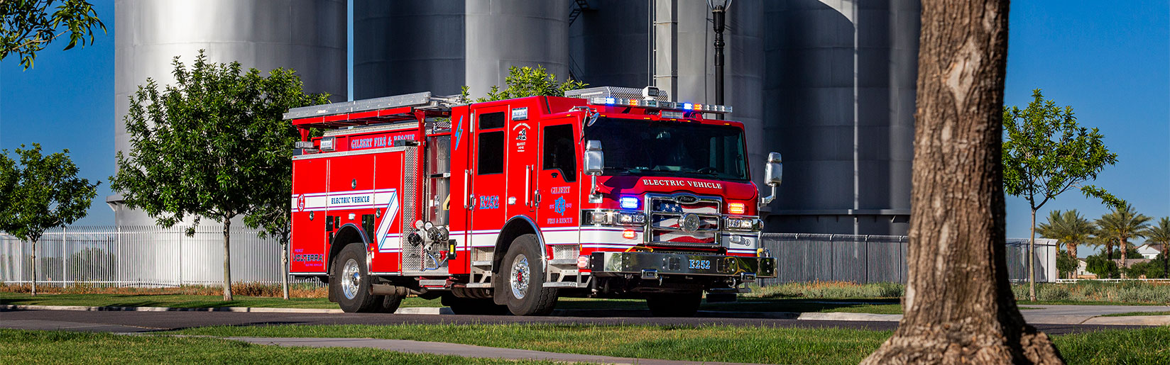 The front officers side of a Velocity® Volterra™ Electric Vehicle parked in front of silos on a sunny day.