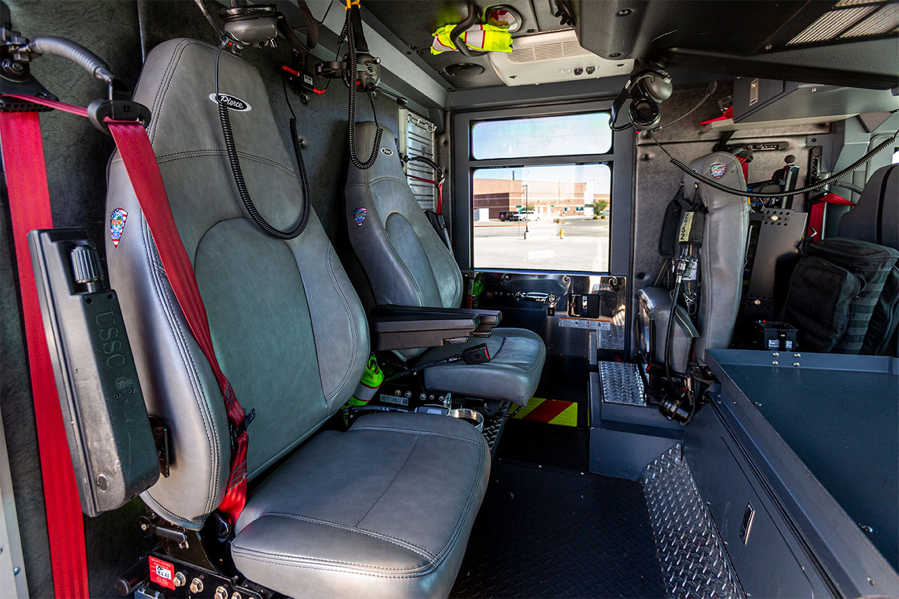 The crew cab of a fire truck with vinyl seats and headsets for firefighters.