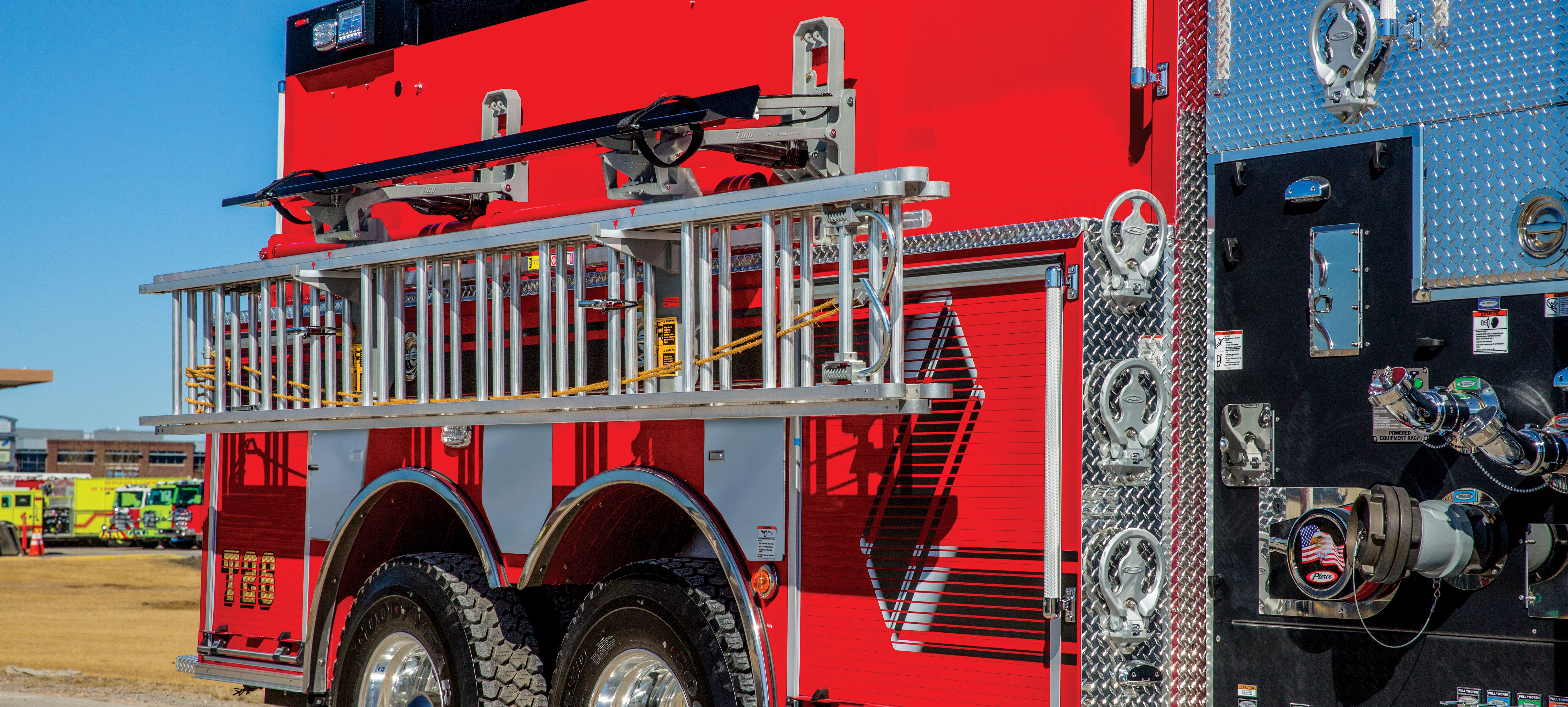 Drop Down ladder rack storage on officer’s side of a Pierce Tanker Fire Truck parked outside on a sunny day. 