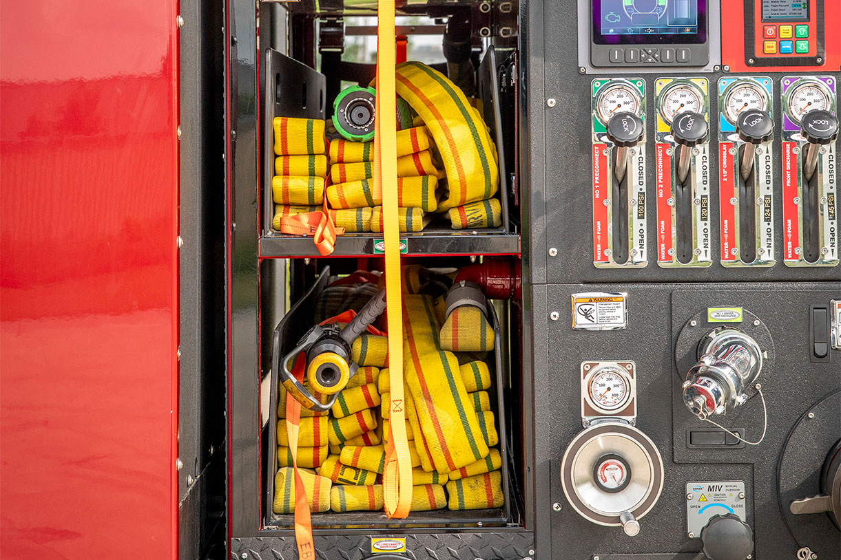 The speedlays of a fire truck with hose in it beside a pump panel.