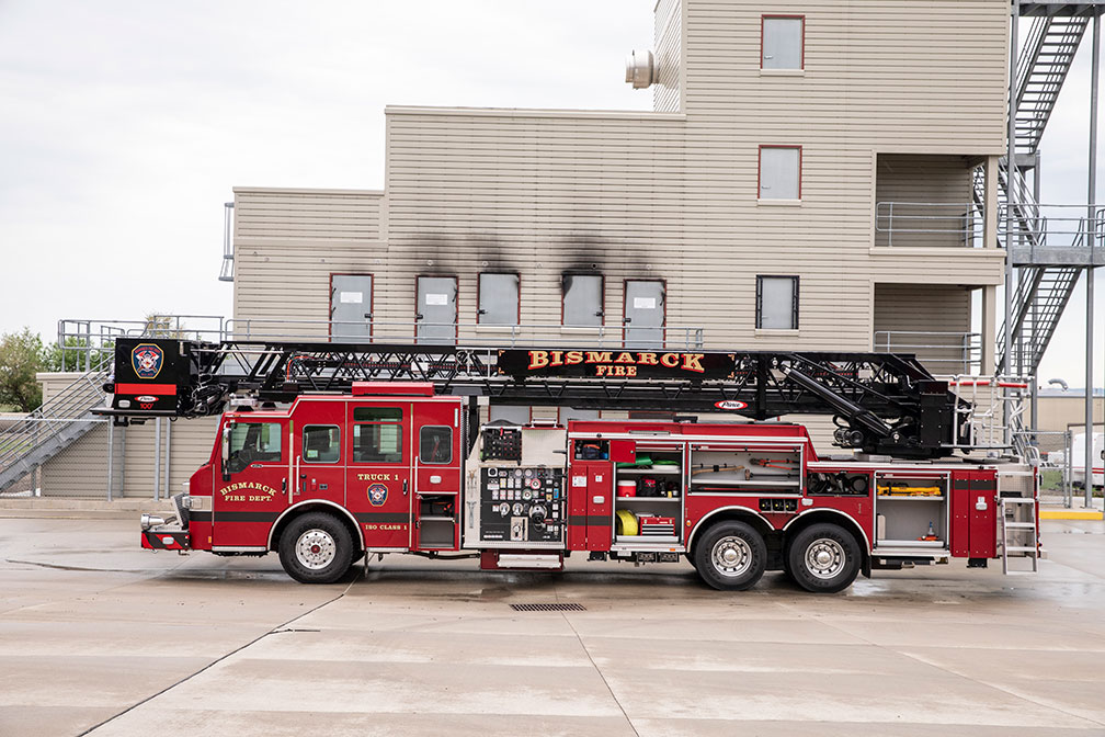 The Driver's side of a Velocity 100' Heavy-Duty Steel Aerial Platform with compartments open showing equipment inside.