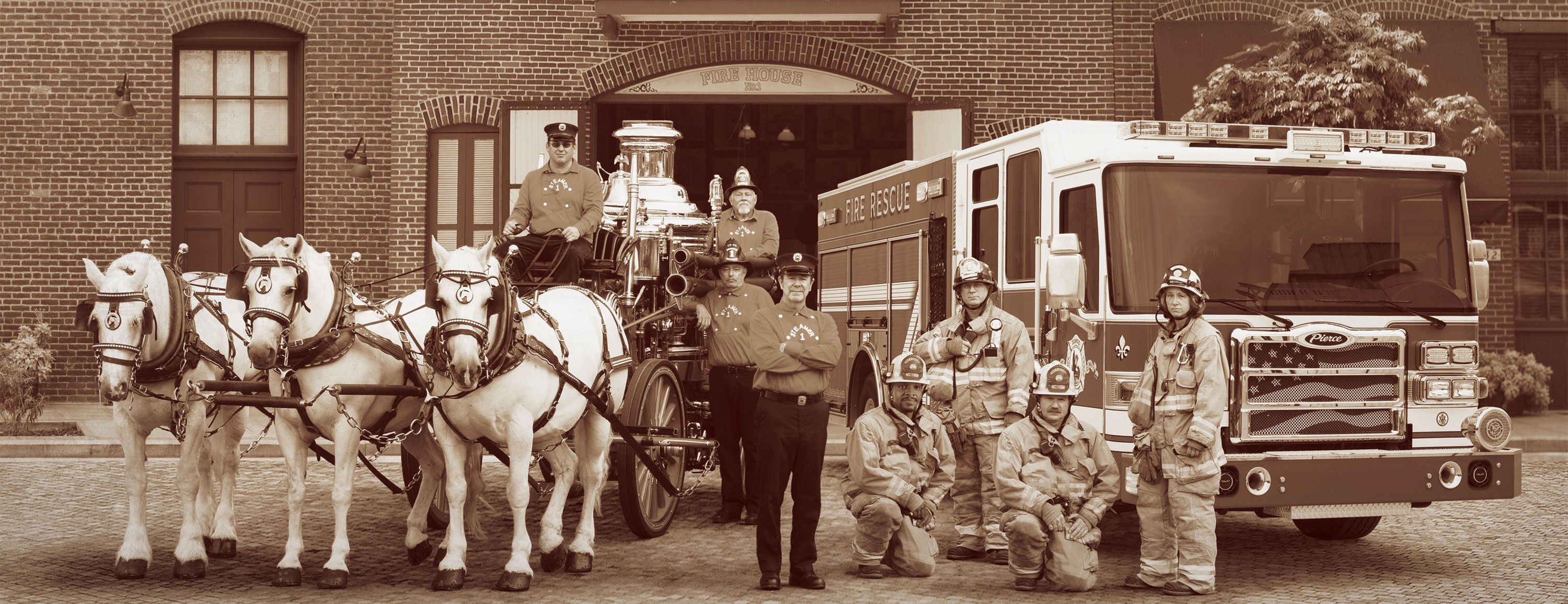 Firefighters next to a Pierce Fire Truck and white horses in front of a Fire Station.