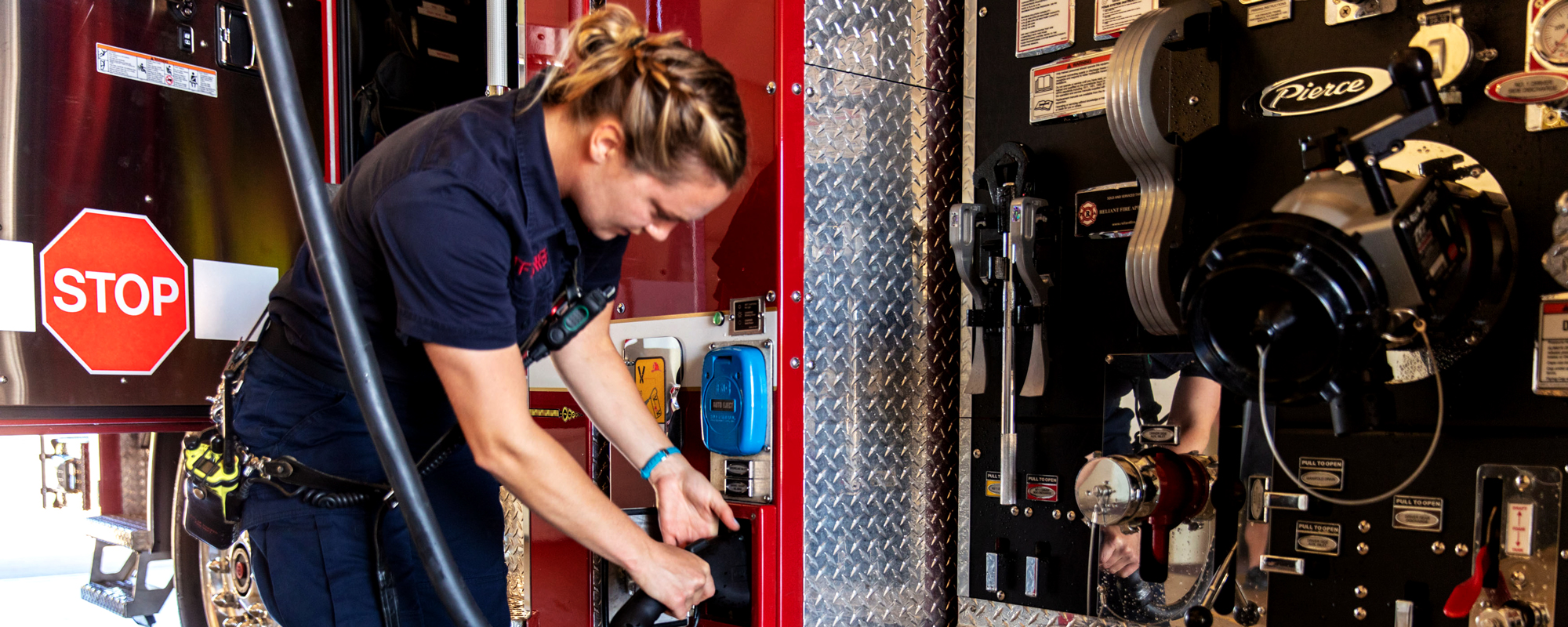 Firefighter plugging Pierce Volterra electric fire truck into charging station. 